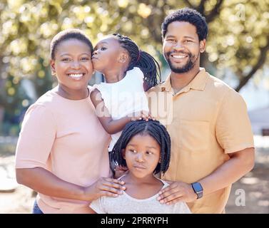 Black family, outdoor fun and smile of parents bonding and spending free time with their children on a sunny day. Portrait of happy man and woman standing in a park or nature with their cute girls Stock Photo