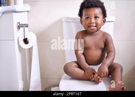 Im ready for my first potty training lesson. an adorable baby boy sitting on the toilet in the bathroom. Stock Photo