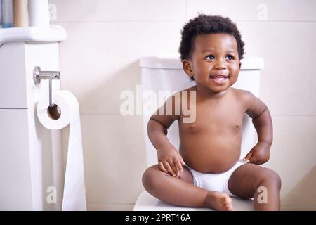 Im gonna ace this potty training thing. an adorable baby boy sitting on the toilet in the bathroom. Stock Photo