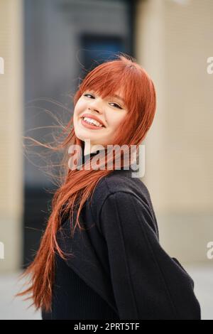 Street portrait of a happy young red-haired woman in a windy day Stock Photo
