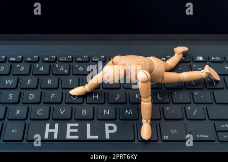 Online HELP button. Wooden dummy trying to reach HELP button on a computer keyboard. Stock Photo