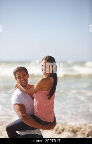 We dont need anything else but eachother. a young couple being playful on the beach. Stock Photo