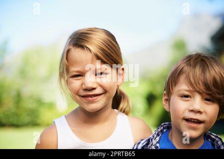 Enjoying a sunny summers day with my sibling. Portrait of a young girl and boy standing outside. Stock Photo