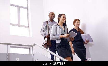 Our office team is on the move. a colleagues taking together in a stairwell. Stock Photo