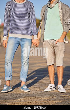 Hand in hand through life. a young gay couple enjoying a walk on the promenade together. Stock Photo