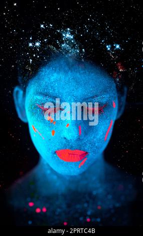 Galactic beauty. a young woman posing with neon paint on her face. Stock Photo