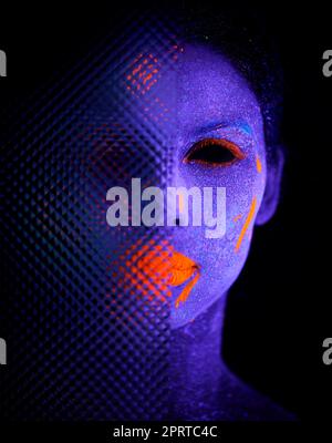 Dark revelations. a young woman posing with neon paint on her face. Stock Photo