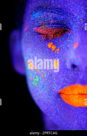 Imagine...a young woman posing with neon paint on her face. Stock Photo