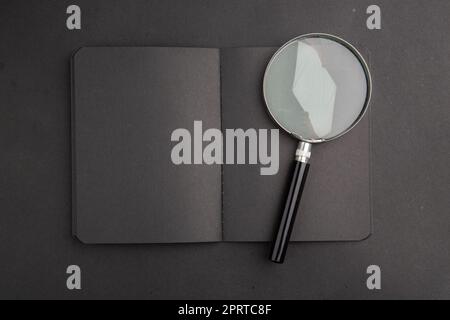 top view black notebook lupa on dark background Stock Photo