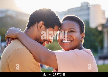Happy african couple hugging in outdoor garden on romantic picnic date together during summer time. Smile, love and care between a black man and woman embracing each other while standing outdoors. Stock Photo
