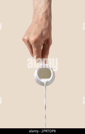 Hand holds milk pot Stock Photo