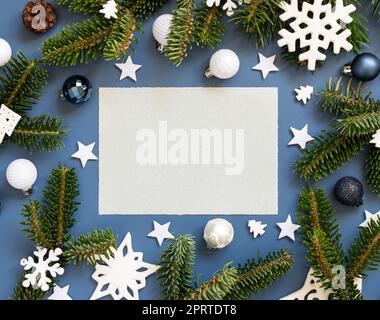 Blank card on a blue background near white Christmas decorations and fir branches Stock Photo