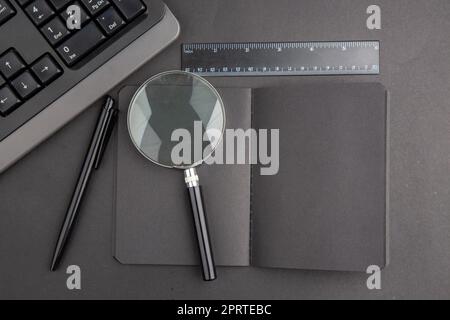 top view black notebook pen keyboard lupa ruler on dark background Stock Photo