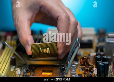 Electronic engineer hand putting computer chip on socket. Chipset on electronic circuit board of PC mother board. CPU chip. Electronic components. Computer hardware. Upgrade computer processor chip. Stock Photo