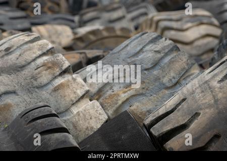 Closeup used truck tires. Old tyres waste for recycle or for landfill. Black rubber tire of truck. Pile of used tires at recycling yard. Material for landfill. Recycled tires. disposal waste tires. Stock Photo