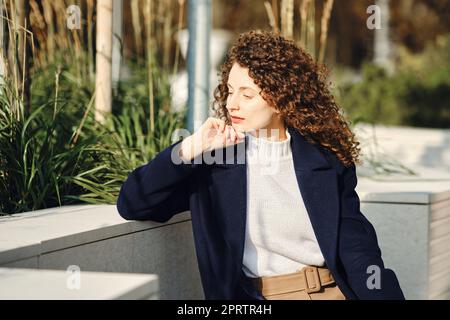 Pensive young woman sitting on a bench in the city Stock Photo