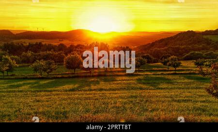 Sunset in Saarland on a meadow with trees and view into the valley. Stock Photo