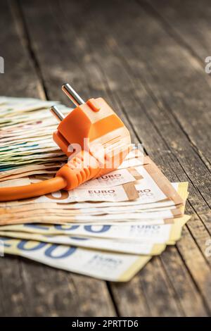 Electric plug and euro money on wooden table. Concept of increasing electric prices. Stock Photo