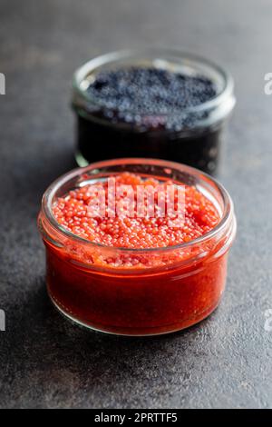 Red and black caviar in jar on dark table. Stock Photo
