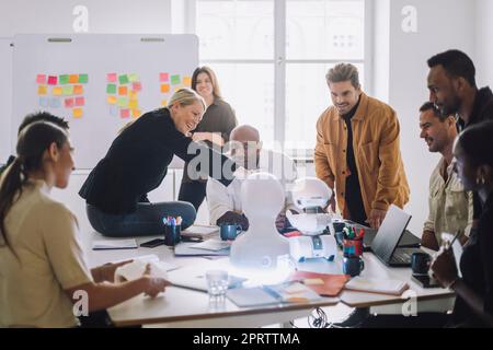 Mature female teacher explaining multiracial students over social robot in innovation lab Stock Photo