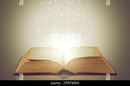 Be drawn into new worlds. an open storybook with light emanating from it. Stock Photo