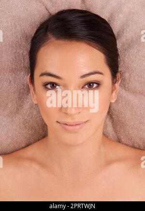 Let the pampering being. A beautiful young woman relaxing on a massage table before her massage. Stock Photo