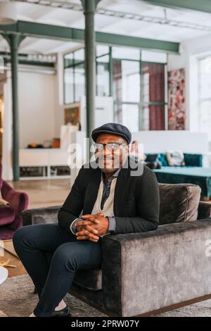 Smiling businessman looking away while sitting on sofa at office Stock Photo