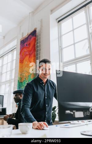 Smiling young businessman using desktop PC at desk in office Stock Photo