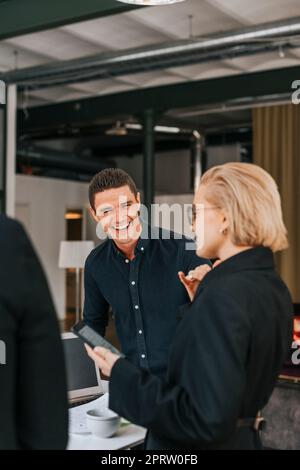 Happy businessman laughing while talking to female colleague at office Stock Photo