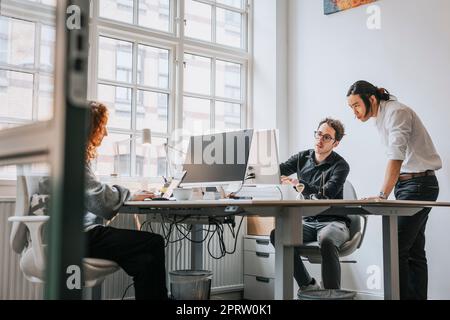 Businessmen discussing over desktop PC at desk in office Stock Photo