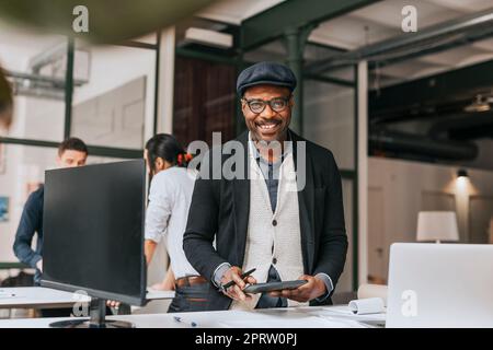 Portrait of smiling businessman with tablet PC standing at desk in office Stock Photo