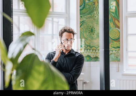 Contemplative businessman talking on smart phone at office Stock Photo