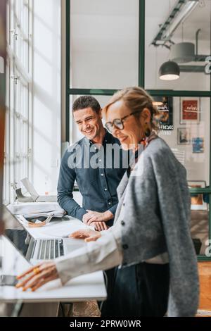 Happy male and female business people at desk in modern office Stock Photo