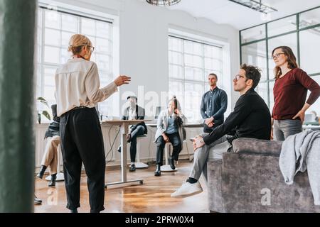 Female manager discussing in meeting with colleagues at modern office Stock Photo