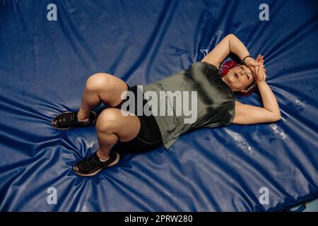 High angle view of tired female athlete lying on landing mat at sports court Stock Photo