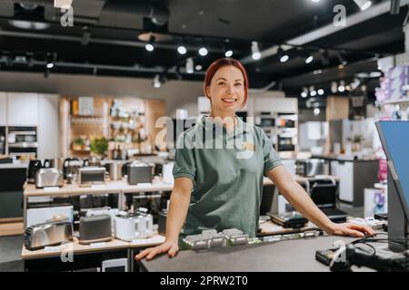 Portrait of smiling female sales clerk standing at counter in electronics store Stock Photo