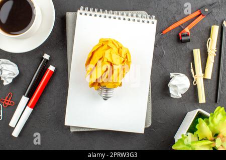 top view cup of tea red and black markers binder clips compasses notebooks on black background Stock Photo