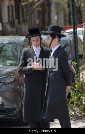 2 Hasidic young men with long peyus chat on a street corner in Brooklyn ...