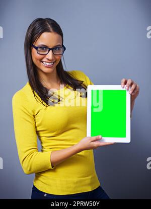 Check out this new website. Studio portrait of an attractive young woman holding a tablet against a blue background. Stock Photo