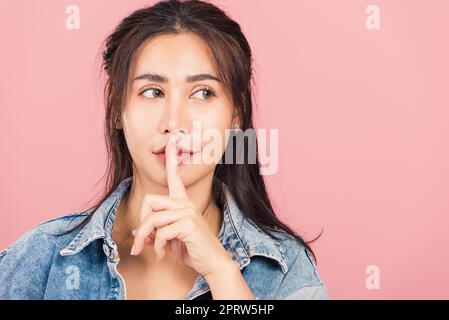woman wear denim smile stand making finger on lips mouth silent quiet gesture Stock Photo