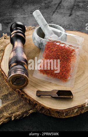 Wooden cross section with saffron in plastic package and mortar and mill Stock Photo
