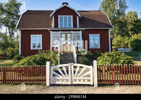 Swedish red and white traditional house in Smalland, White fence green garden blue sky Stock Photo