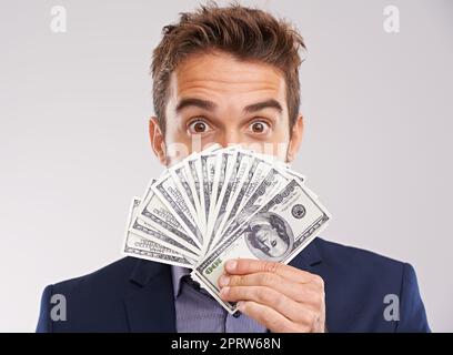 Show me the money. Studio shot of a businessman holding a fan of money in front of his face. Stock Photo
