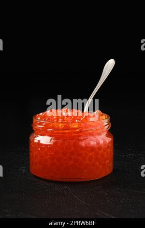 Open jar with red caviar and a spoon in it Stock Photo