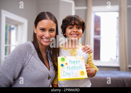 Shes the best mom ever. Portrait of a son holding a mothers day card with his mom. Stock Photo