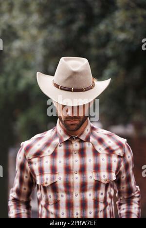 Cowboy couture. a handsome man wearing a check shirt and cowboy hat. Stock Photo