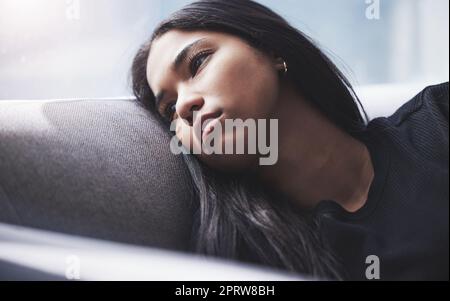 Depression, thinking and sad girl on sofa alone and hopeless with mindset problem in home. Young woman in mental isolation from anxiety, worry and stress about negative thoughts in mind. Stock Photo