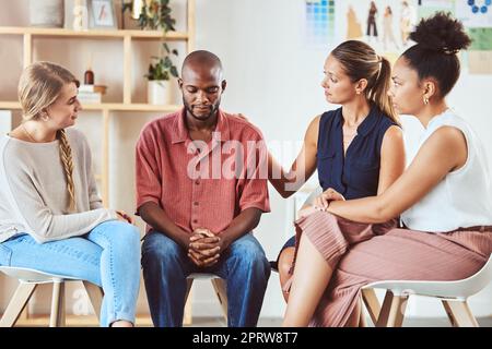 Group therapy, support or mental health community in comfort of sad black man with anxiety, depression or stress. Diversity friends, women or people in counseling in psychology trust meeting for help Stock Photo