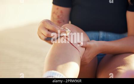 Knee injury and person cleaning blood wound with tissue to stop bleeding for healing and recovery. Self care hygiene after accident with torn and sore skin on leg for infection prevention. Stock Photo