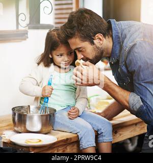 Smells as yummy as it looks. a father and daughter making pancakes together. Stock Photo